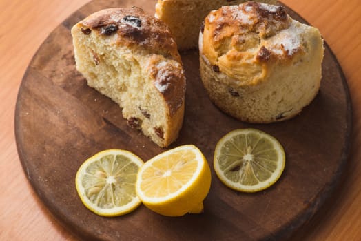 Top view of muffin with lemon in cup and on wooden plank table.