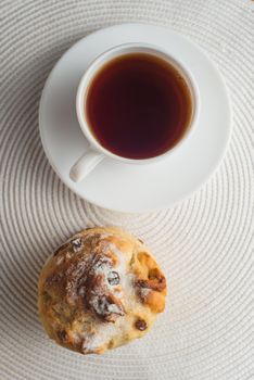 Homemade carrot muffin with cap of tea and lemon on white fabric background. top view