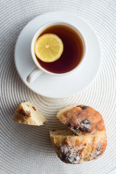 Homemade carrot muffin with cap of tea and lemon on white fabric background. top view