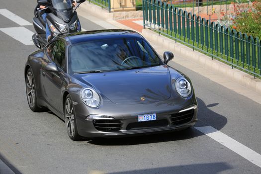 Monte-Carlo, Monaco - May 18, 2016: Beautiful Woman Driving an Expensive Porsche 911 Carrera S on Avenue Princesse Grace in Monte-Carlo, Monaco in the south of France