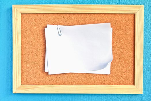 notepad on cork board on sky-blue background