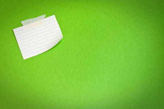 White note paper attached on green background 