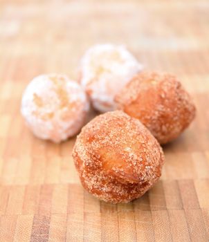 Fresh fried donuts powdered by a sugar on the wooden plate.