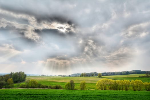 Nature panorama with shining sun behind the clouds. HDR effect.