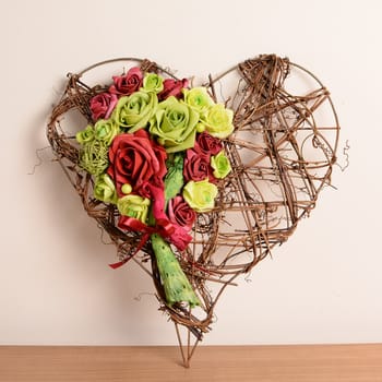 Interior decoration, decorative wicker heart with red and green rose.