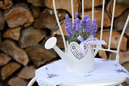 Lavender in the old metal can on the metal chair. Home decoration.