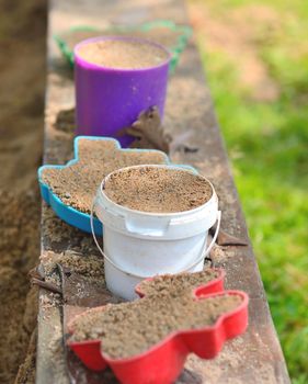 Plastic toys balanced on the border of sandpit.