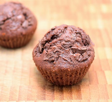 Chocolate muffins on a wooden plate. Closeup shot.