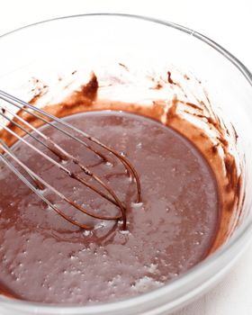 Mixing of a chocolate dough in a glass bowl for making a cake.