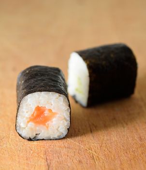 Sushi Hosomaki with salmon and green pepper on a wooden plate.