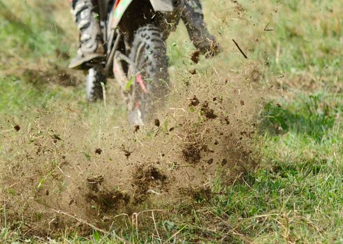 Flying mud from moving motorcycles enduro wheel.