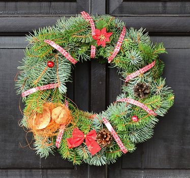 Christmas wreath with red ribbon and nut hanging on the door.