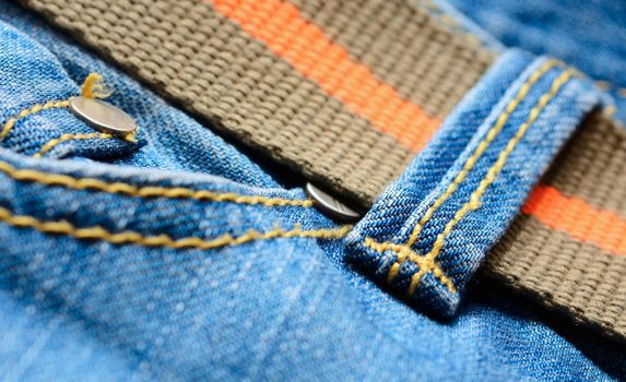 Blue jeans with orange belt, macro shot.