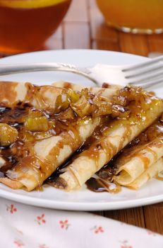 Breakfast pancakes on apples with caramel and chocolate and cup of tea