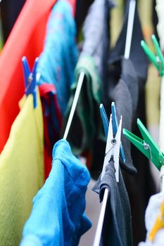 Fresh colorful laundry hang on the clothesline with colorful pegs.