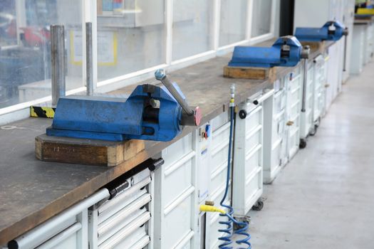 Vice clamps on the bench in the factory hall.