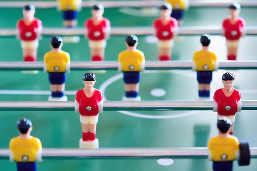 Closeup of the table football or foosball players in red and yellow jerseys.