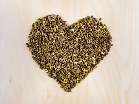 Heart shaped from raw dry brown lentils in cup, top view, center composition, food preparation, copy space, healthy lifestyle, eating legumes