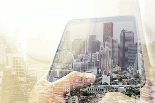 Using digital tablet double exposure and and cityscape background. Business technology concept.