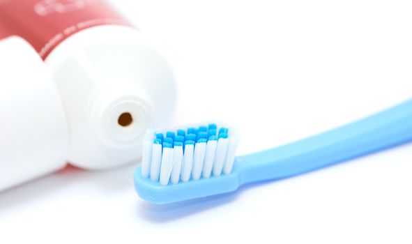 Blue toothbrush and tooth paste tube on white background. Closeup of the daily dental hygiene tool. 