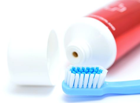 Blue toothbrush and tooth paste tube on white background. Closeup of the daily dental hygiene tool. 