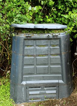 Old dirty composter bin with rotten grass.