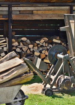 Circular saw with wood logs and log store in garden. Woodworking in garden.