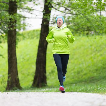 Sporty young female runner in city park.  Running woman. Female runner during outdoor workout in nature. Fitness model outdoors. Weight Loss. Healthy lifestyle. 