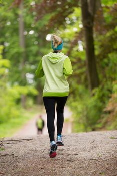 Sporty young female runner in forest.  Running woman. Female runner during outdoor workout in nature. Fitness model outdoors. Weight Loss. Healthy lifestyle. 