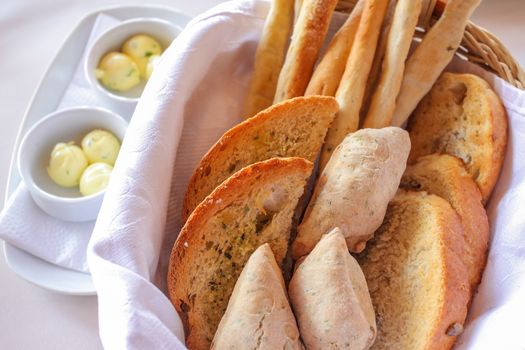 freshly backed various bread, tost, bagettes, served in a basket with white napkin.