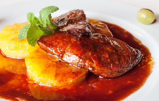 Luxuriously served roasted goose liver over orange slices with sauce and fresh mint meal.