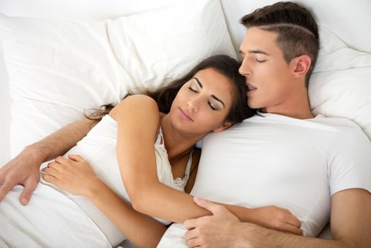 Young hugging couple sleeping on the bed in bedroom