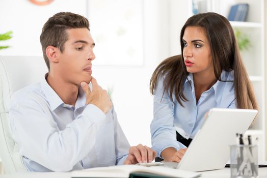 Young beautiful businesswoman and businessman working on laptop in the office.