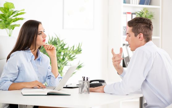 Happy successful businesswoman discussing with male colleague in the office.