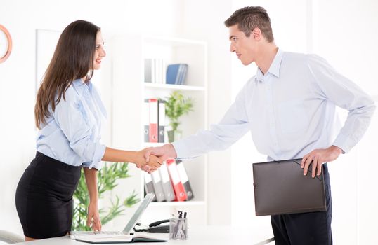 Happy successful businesswoman and businessman shake hands after meeting in the office.