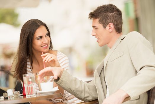 Young couple in garden cafe flirts and enjoys the coffee.