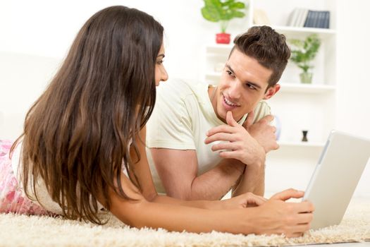 Happy couple at home looking at laptop and surfing internet