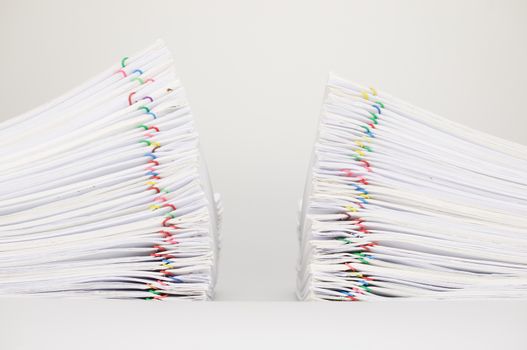 Dual pile overload document of report with colorful paperclip place on white background.