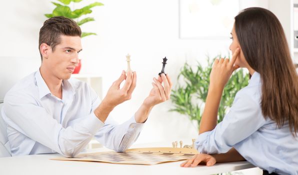 Young businessman and businesswoman playing chess in the office.