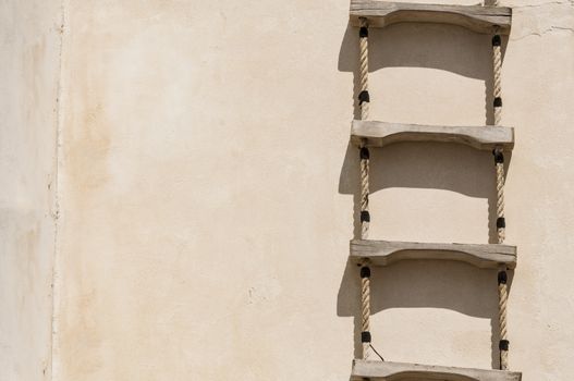 Ladder with rope hanged on a wall