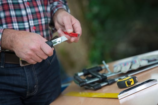 Sharpening of a carpenter's pencil with a blade knife outdoor