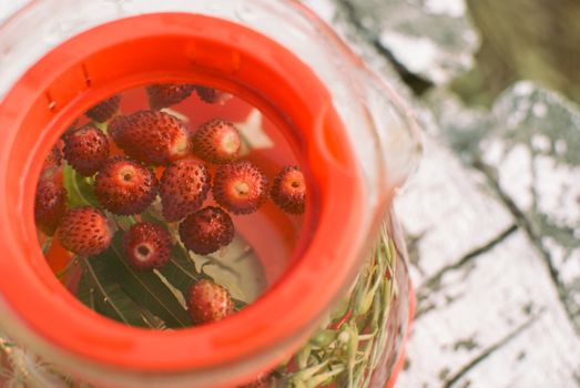 teapot of fruit tea with herbs and berry on the white tree stump.