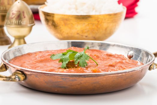 Closeup photo of a pan of Indian butter chicken garnished with cilantro.