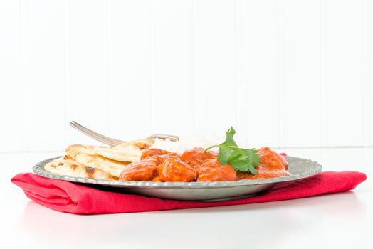 Plate with Indian butter chicken, rice and nan bread.