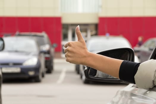 girl makes a gesture with his hand out the window of a passenger car white