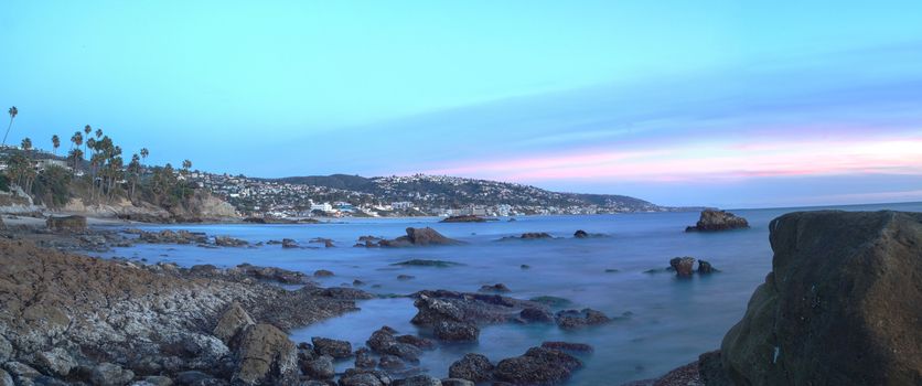 Long exposure of sunset over rocks, giving a mist like effect over ocean in Laguna Beach, California, United States