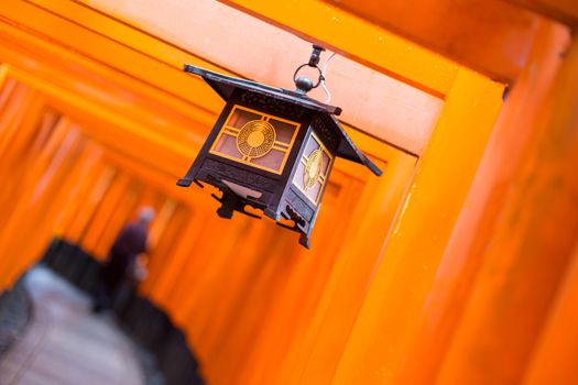 Red Tori Gate at Fushimi Inari Shrine in Kyoto, Japan. Selective focus on traditional japanese lamp.