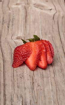 Sliced ripe strawberry on a rustic farm picnic table in summer.