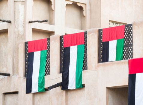 The flag of The United Arab Emirates draped over a traditional Arabic house in Dubai.