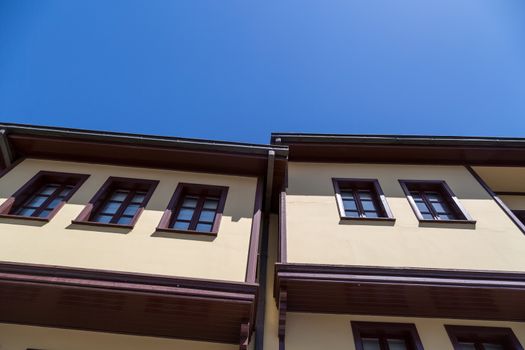 Close up bottom view of historical old colorful Odunpazari houses on bright blue sky background.